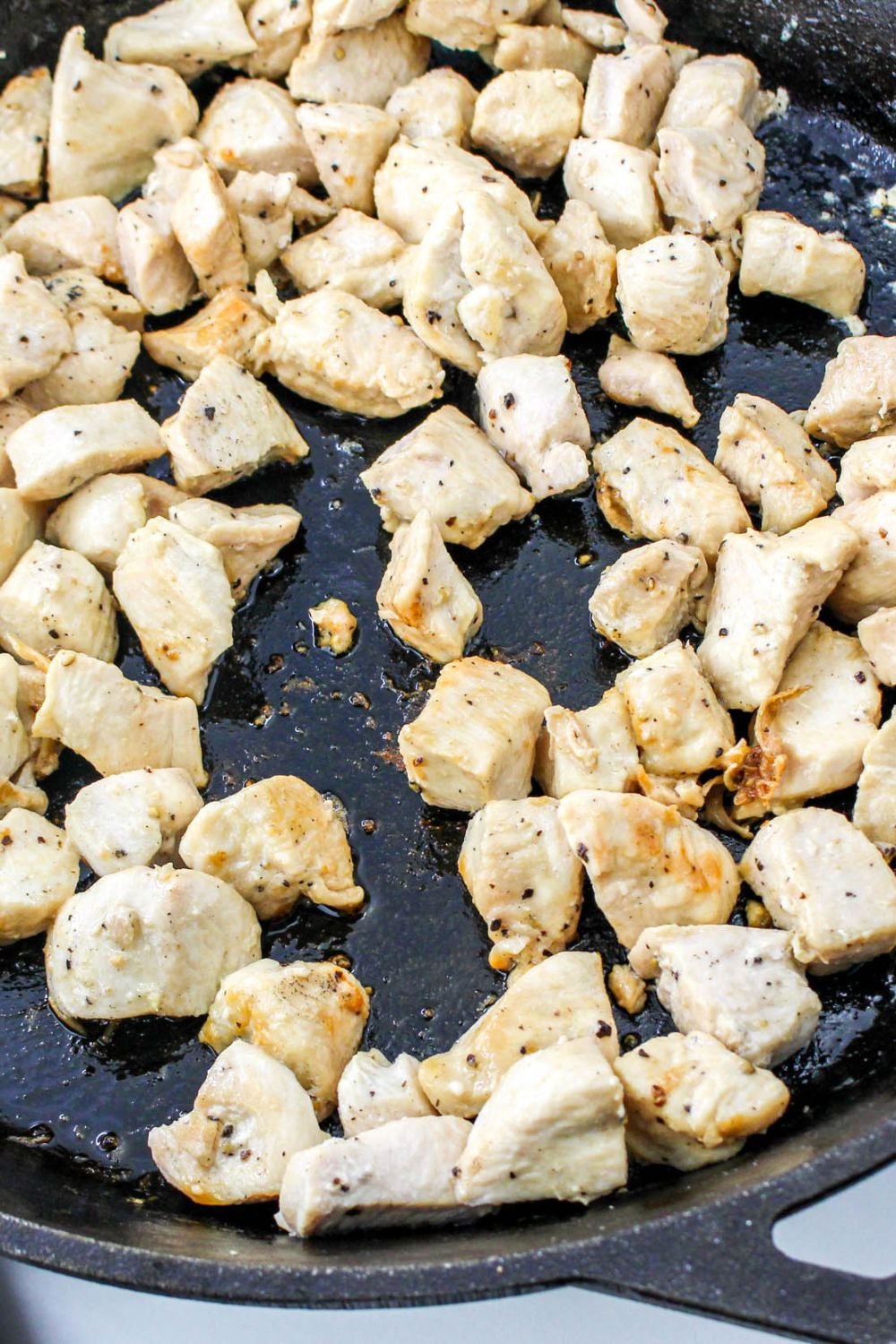 seared chicken in a skillet that is diced into bite size pieces