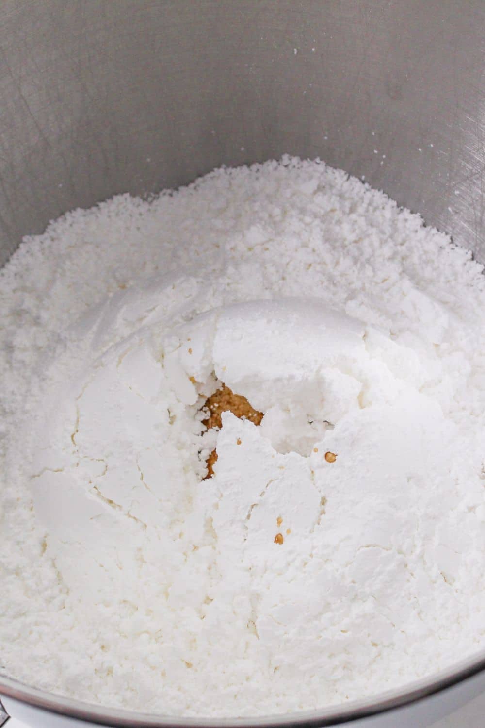 powdered sugar and vanilla extract in a metal mixing bowl