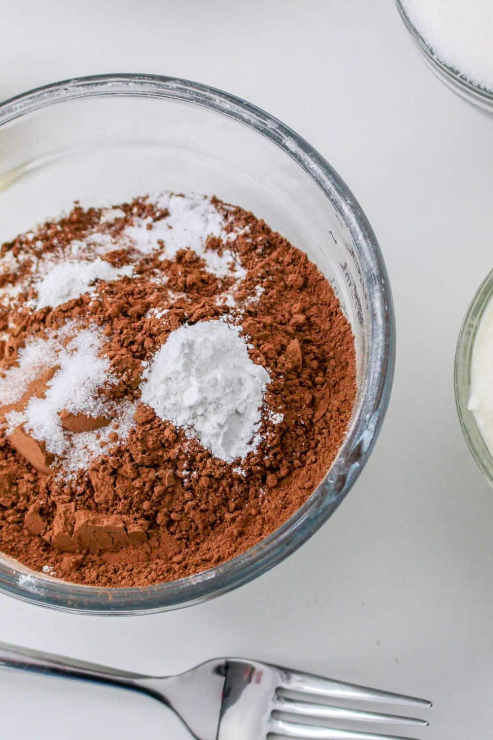 dry ingredients in a small bowl on table for adding to cake. -Flour, cocoa powder, baking soda, baking powder, salt.