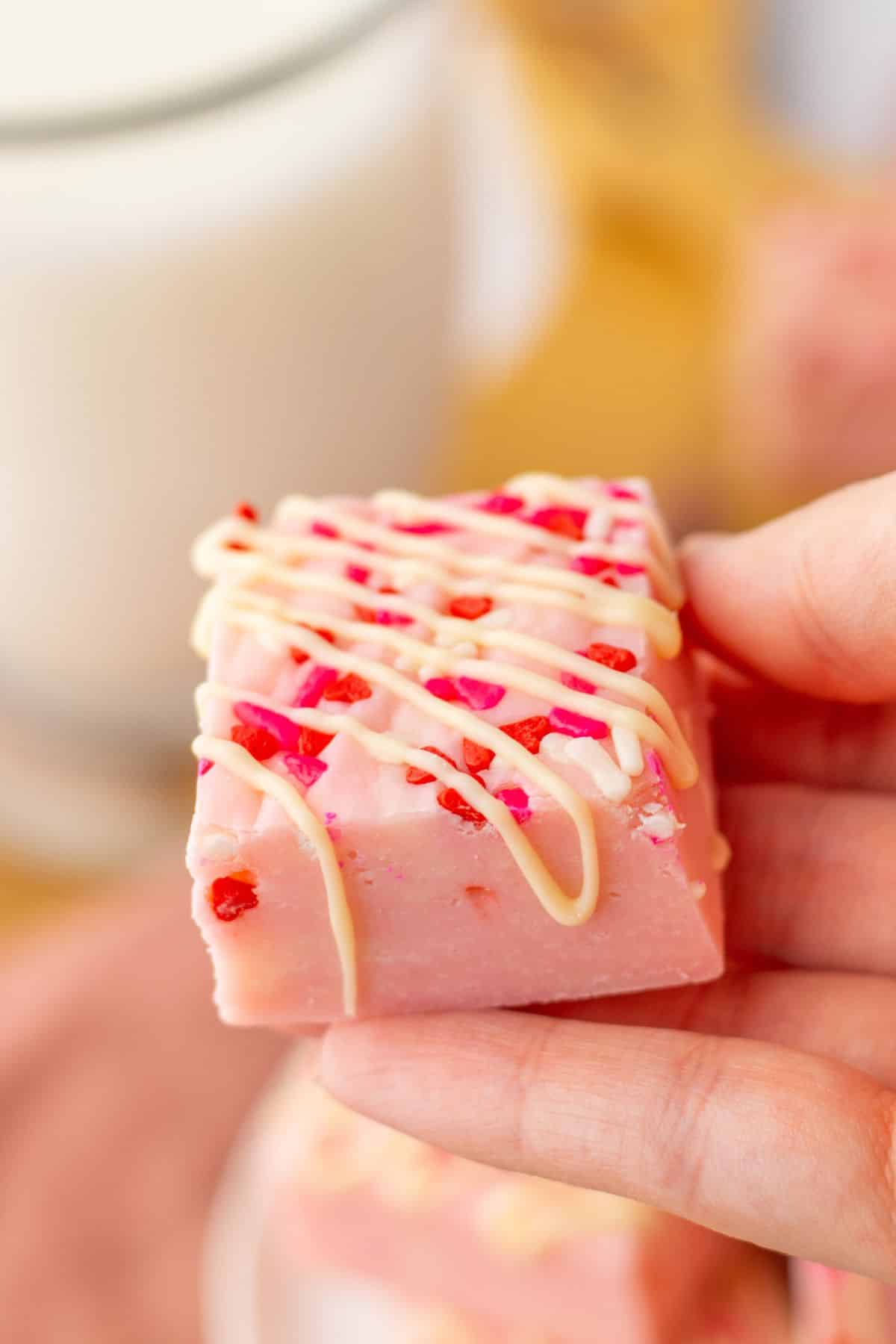 slice of pink sugar cookie fudge held in a woman's hand.