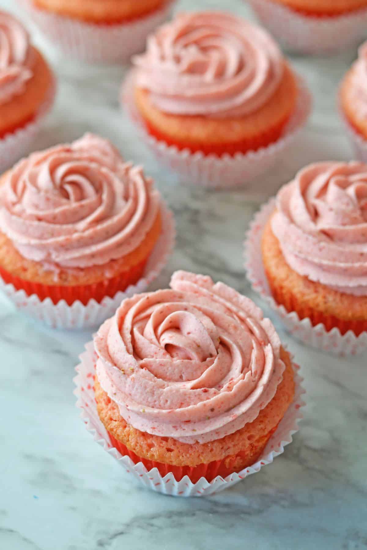strawberry champagne cupcakes on a marble counter.