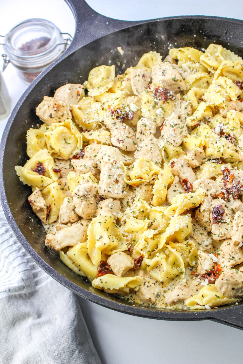 large skillet with chicken and tortellini smothered in a creamy sauce