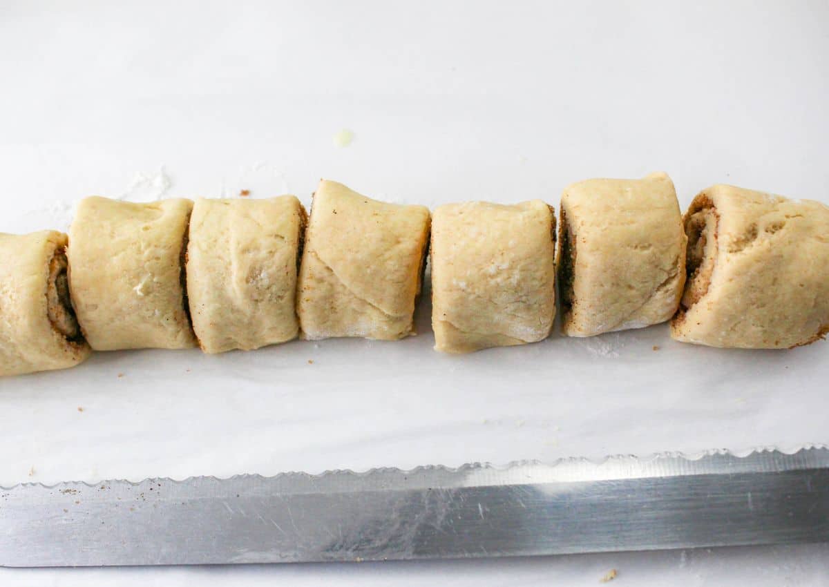 cinnamon sugar crescent roll dough being sliced into 12 pieces.