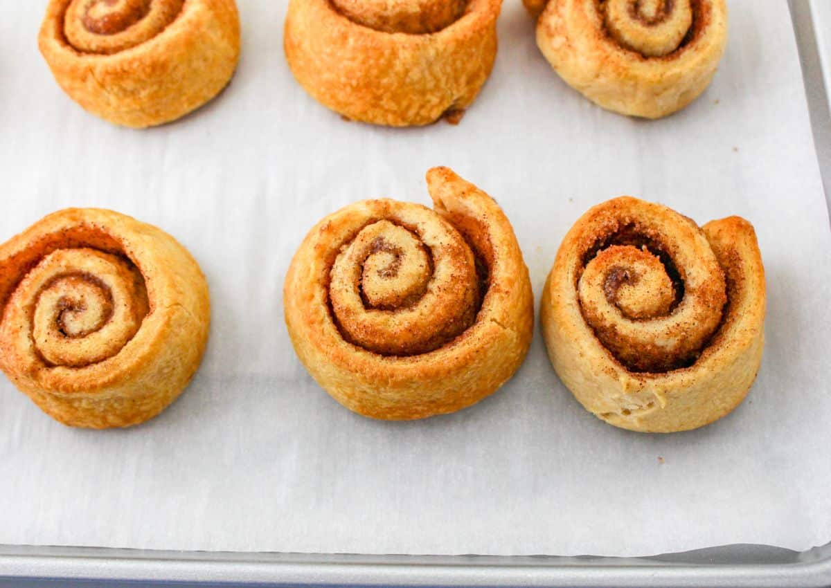 cinnamon rolls cooling on a parchment lined baking sheet.