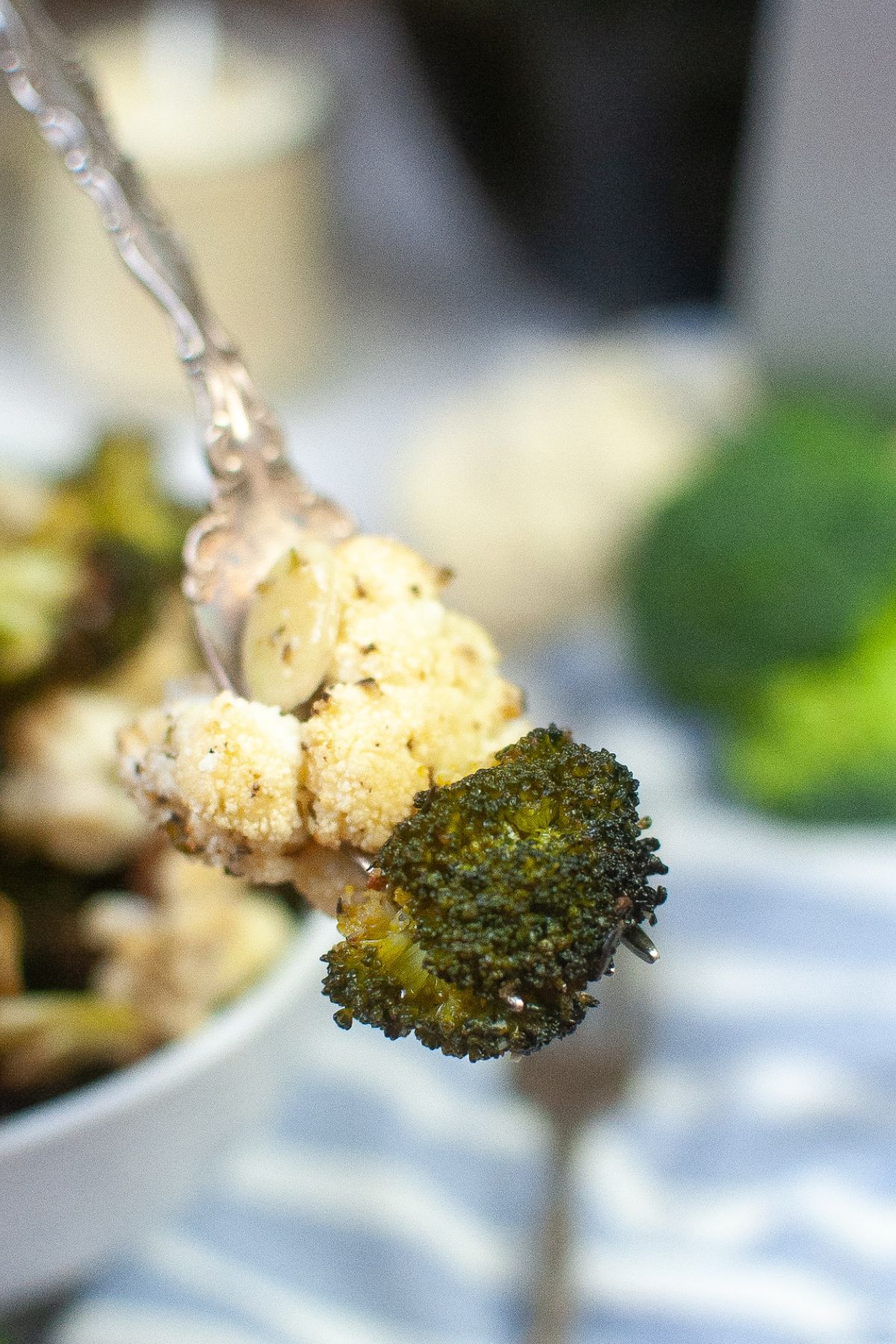piece of broccoli and cauliflower on a fork held in the air.