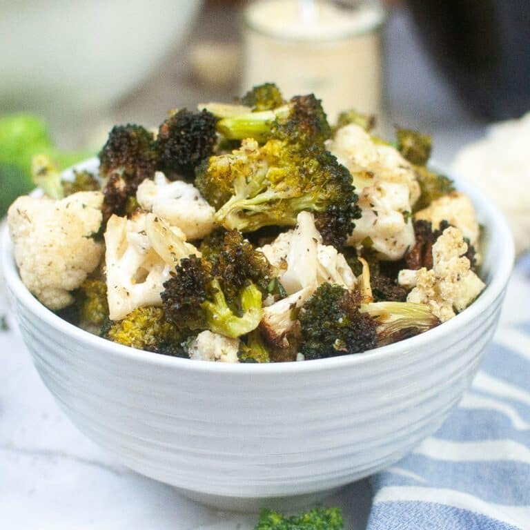 bowl full of seasoned air fryer broccoli and cauliflower.