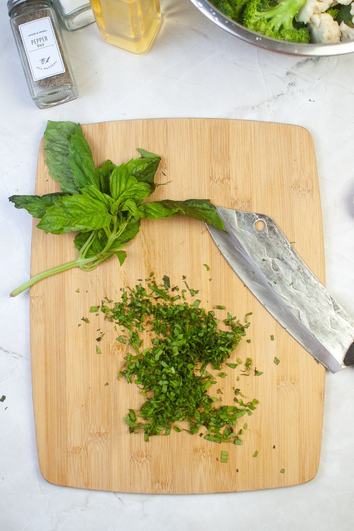 basil being chopped on a wooden cutting board.