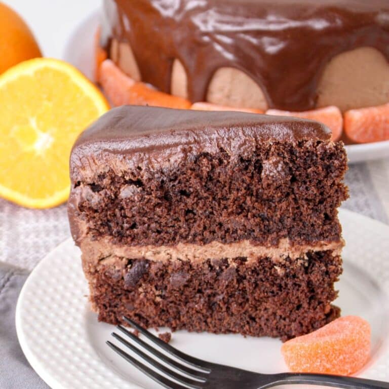 slice of chocolate orange cake on a plate with a fork and a candied orange slice.