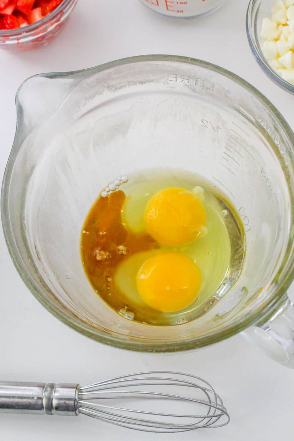 eggs and vanilla in a mixing bowl with a whisk sitting on table