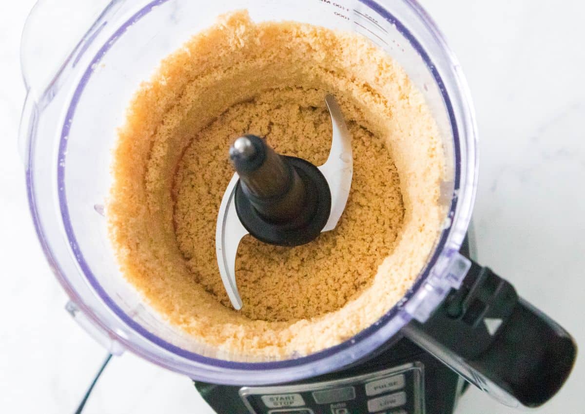 golden oreo cookies being crushed in a food processor.