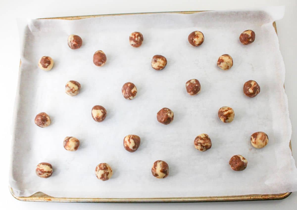 cookie dough balls on a parchment lined baking sheet ready for the oven.