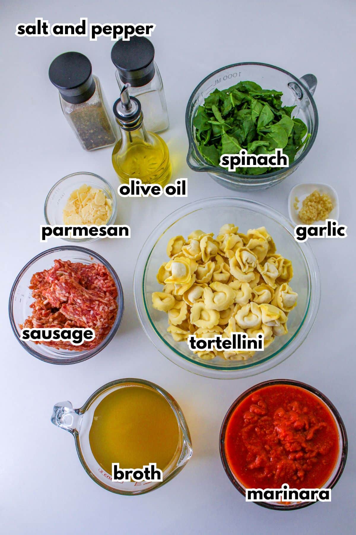 bowls of salt and pepper, olive oil, spinach, sausage, parmesan, garlic, tortellini, broth, and marinara sauce.