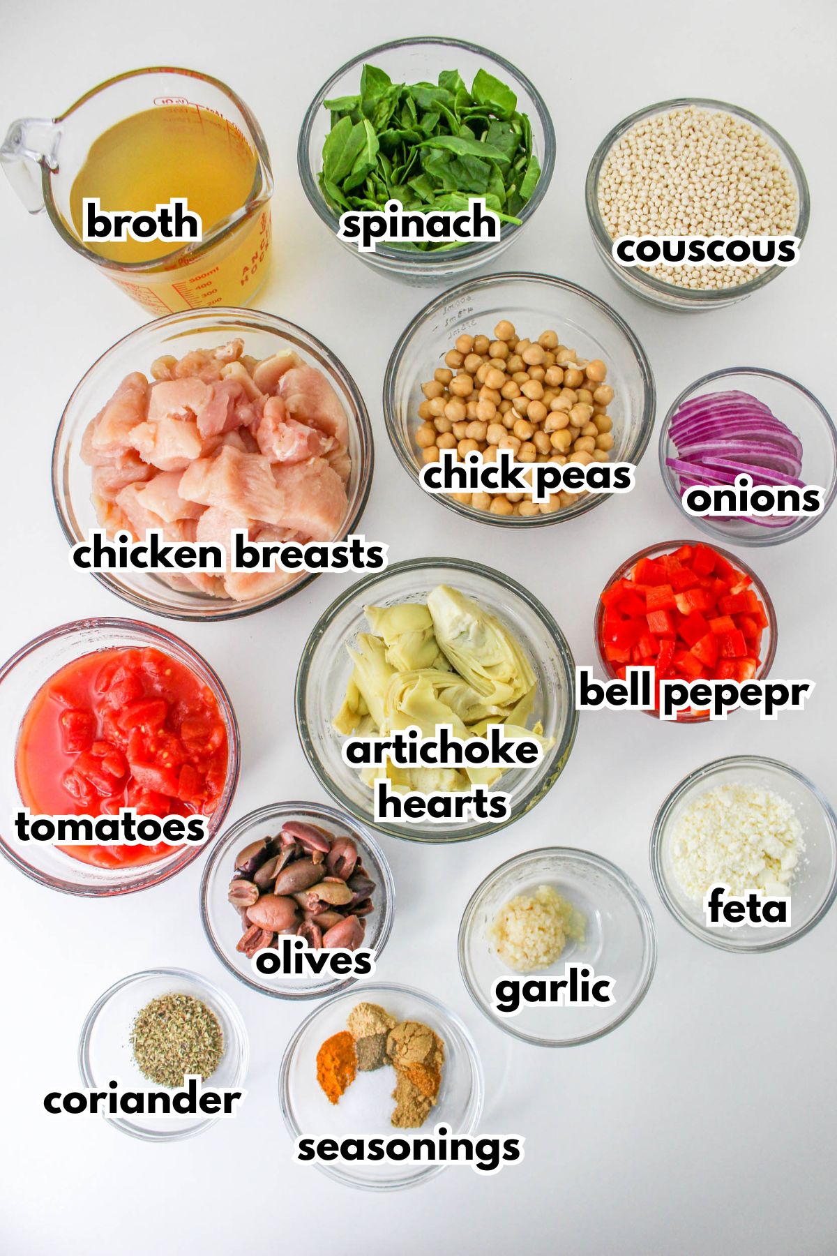 bowls of ingredients needed to make mediterranean chicken on a counter.