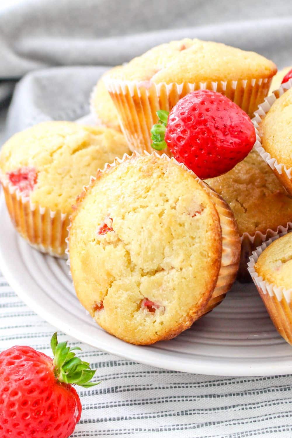Strawberry White Chocolate Chip Muffins on a plate and fresh berries around the muffins