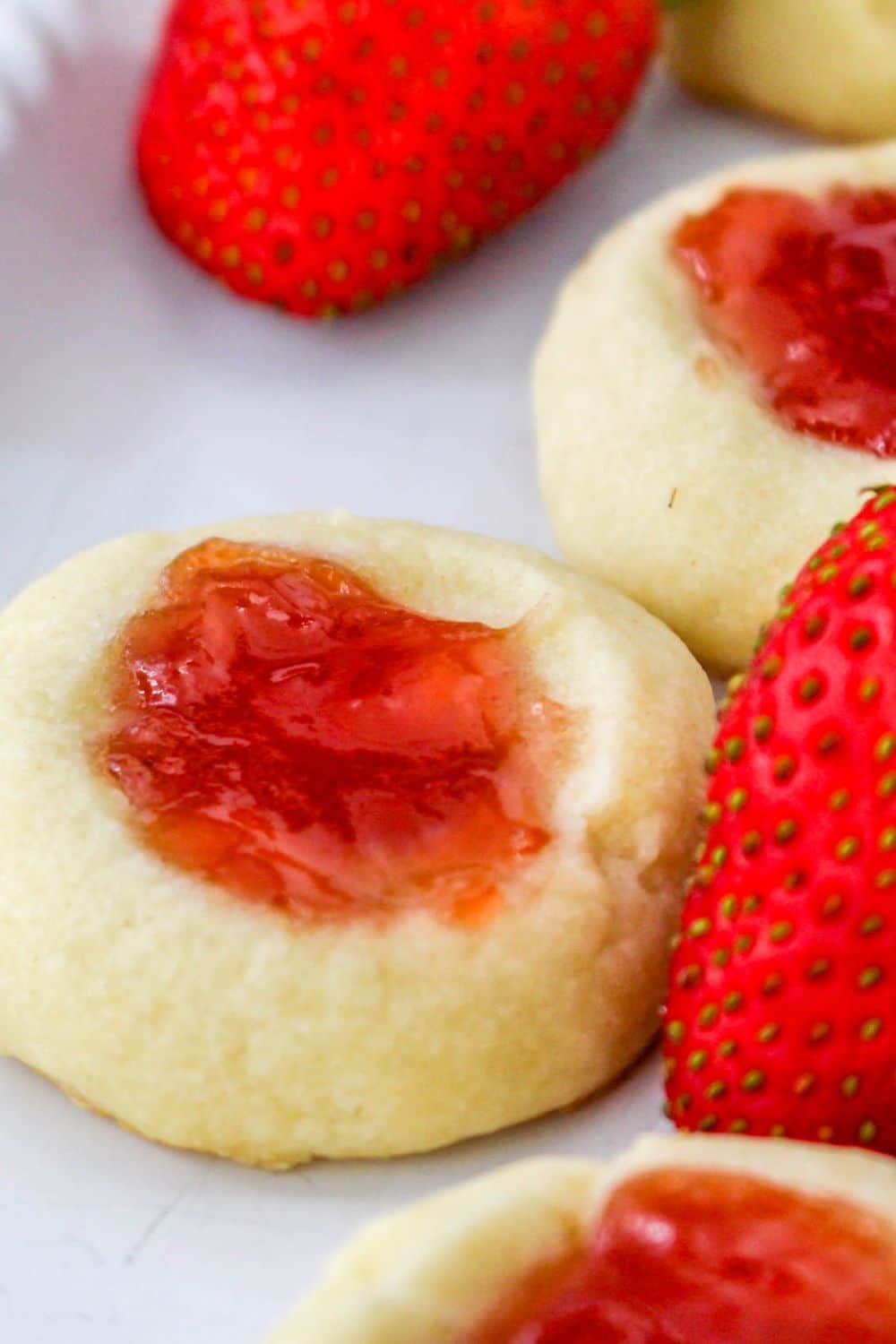 strawberries on tray with thumbprint jam cookies around the berries