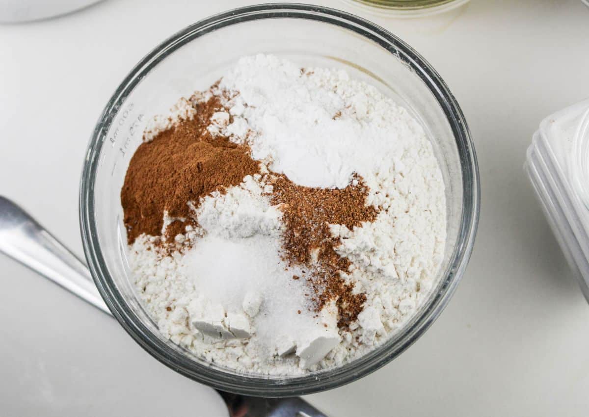 flour, cinnamon nutmeg, salt, baking powder and baking soda being mixed in a small glass bowl.
