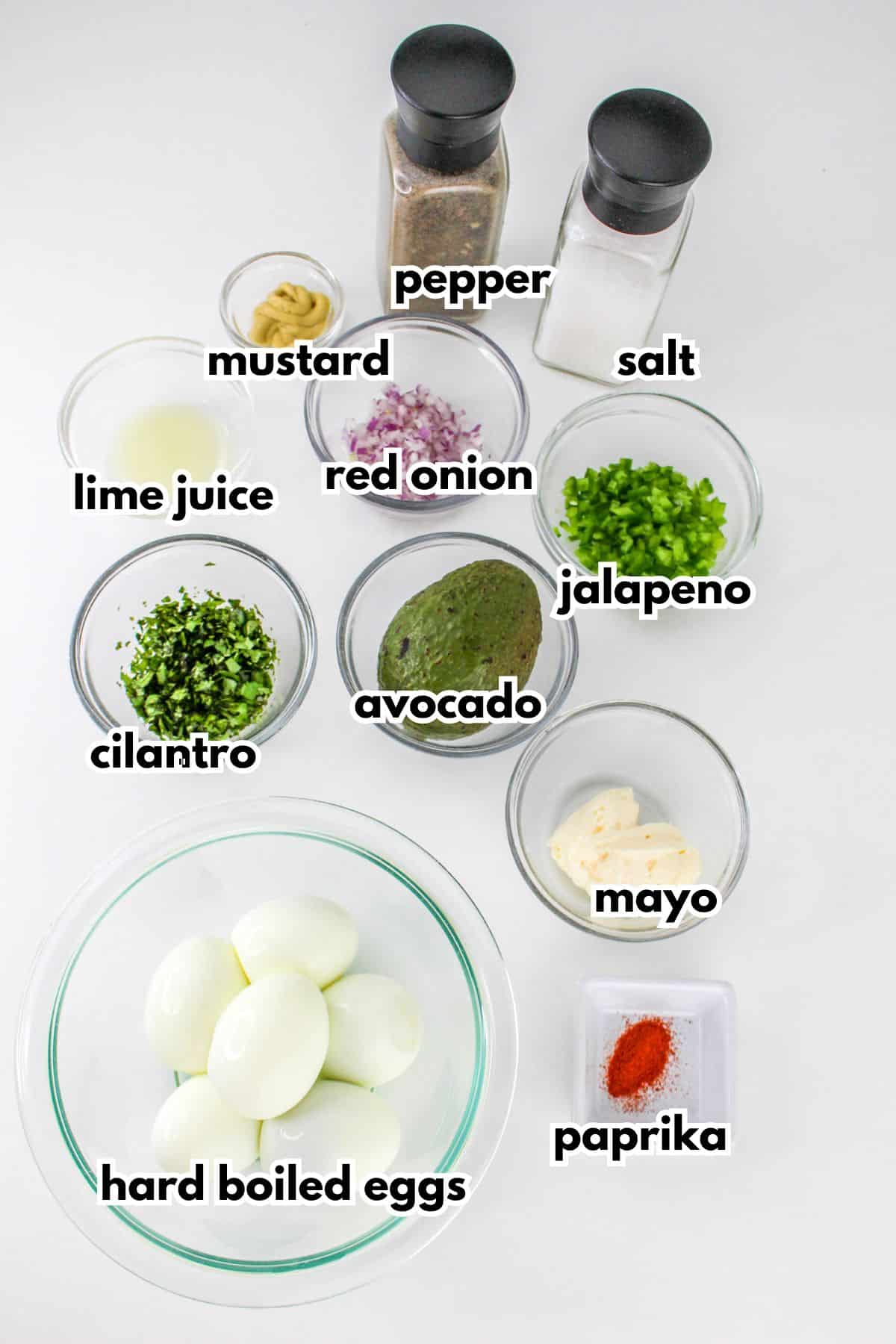 bowls of mustard, lime juice, cilantro, red onion, avocado, jalapeno, hard boiled eggs, mayo, paprika, pepper and salt.