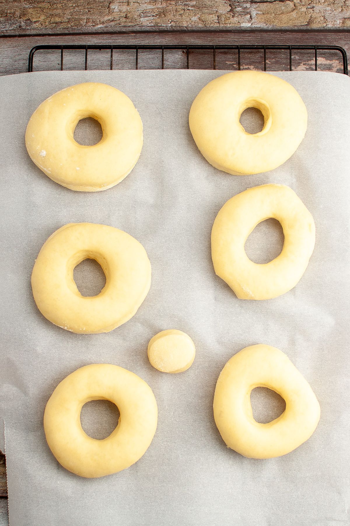 raw doughnuts rising on a baking sheet.