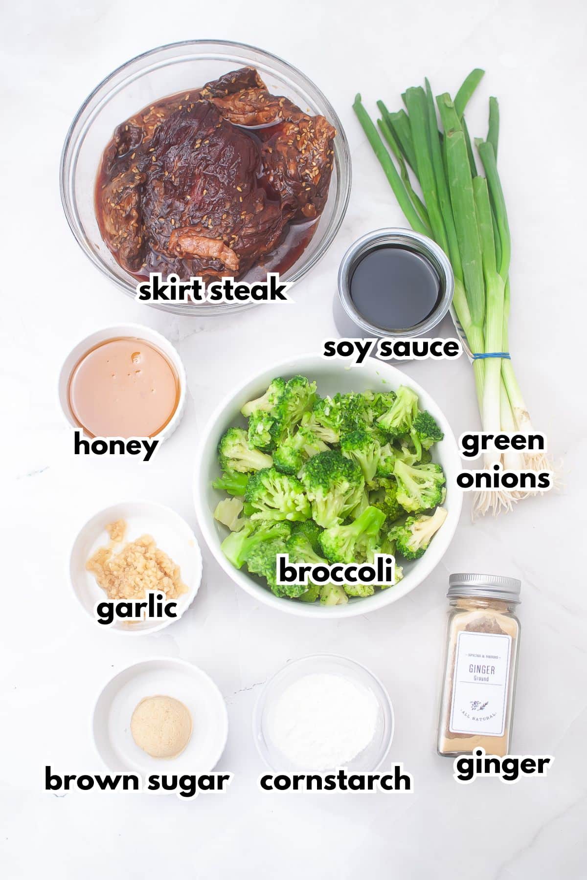 bowls of skirt steak, honey, soy sauce, green onions, garlic, broccoli, brown sugar, cornstarch, and ginger on a counter.