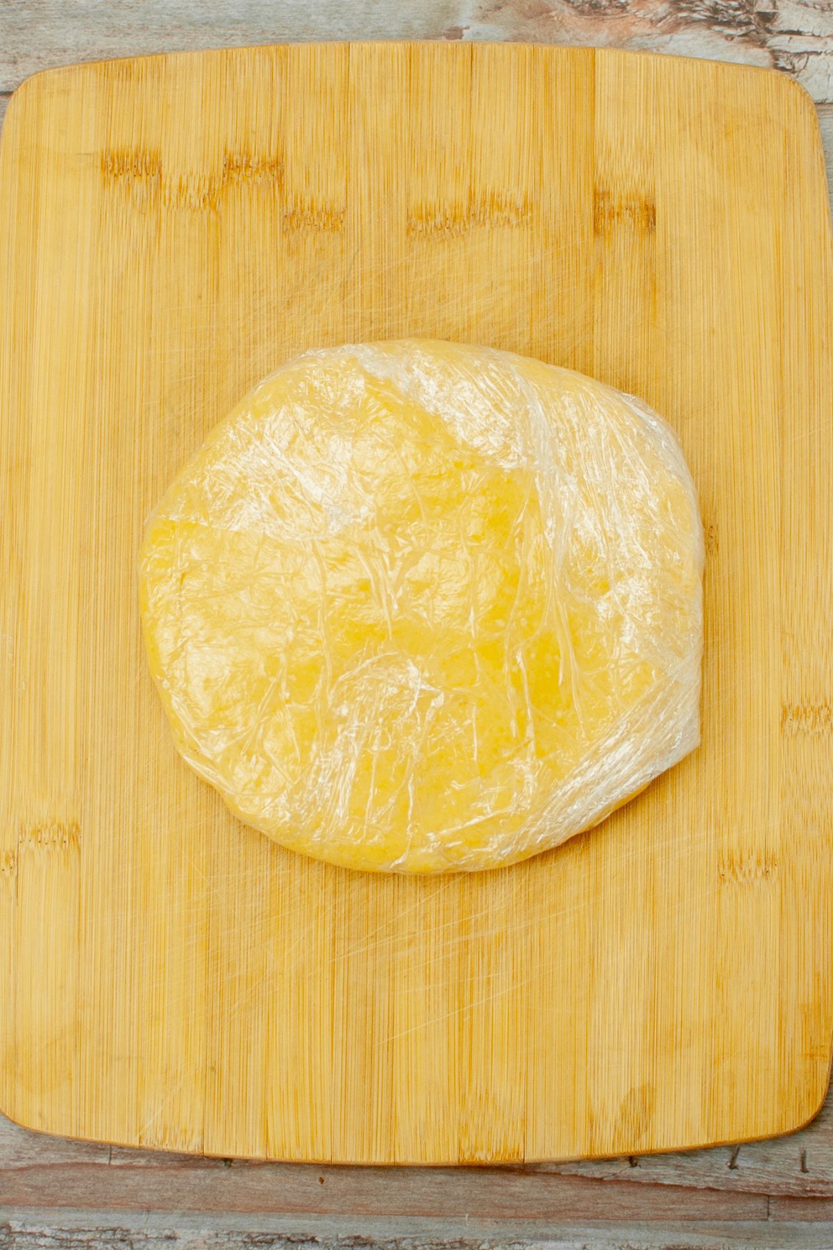 cheese dough shaped into a disc and wrapped in plastic wrap.
