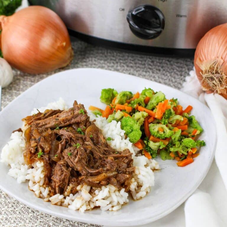 shredded braised steak and onions on top of a bed or rice.