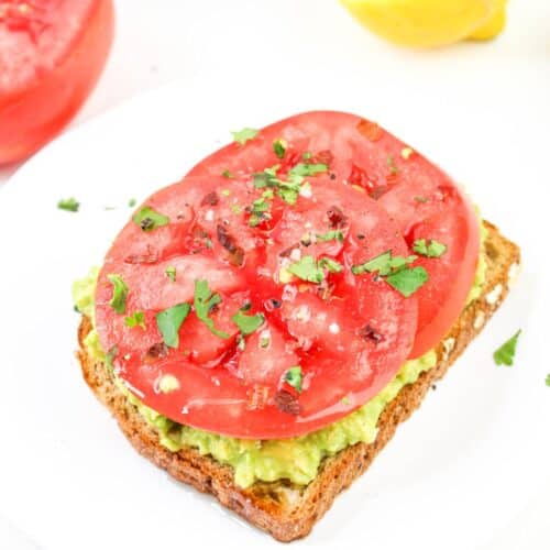 slice of avocado toast with tomatoes on a plate.
