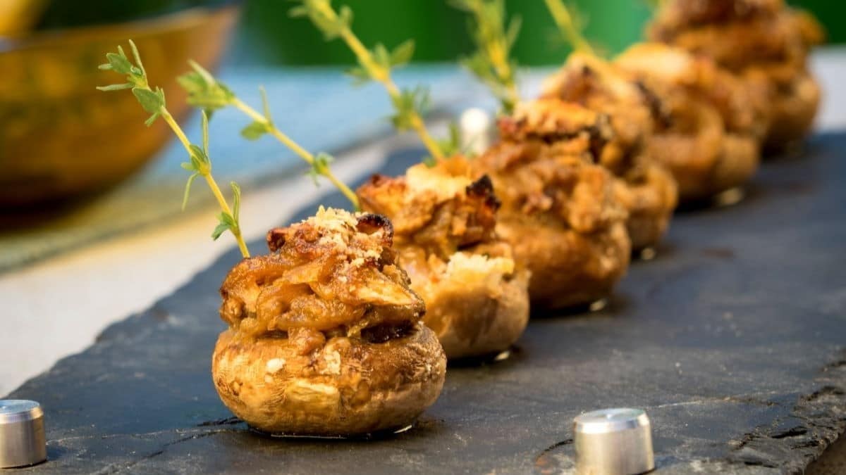 A row of cheese stuffed crispy mushrooms with herb accents.