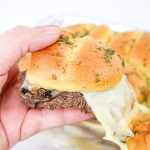 steak and cheese sandwich held in a woman's hand.