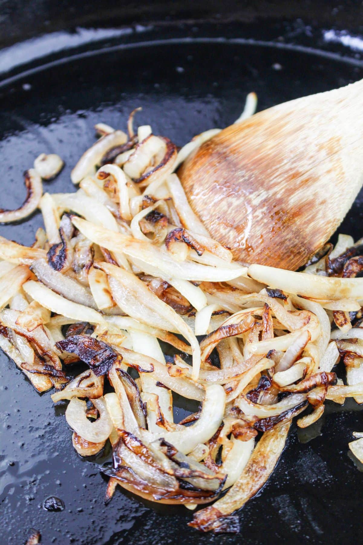 onions being sauteed in a cast iron skillet.