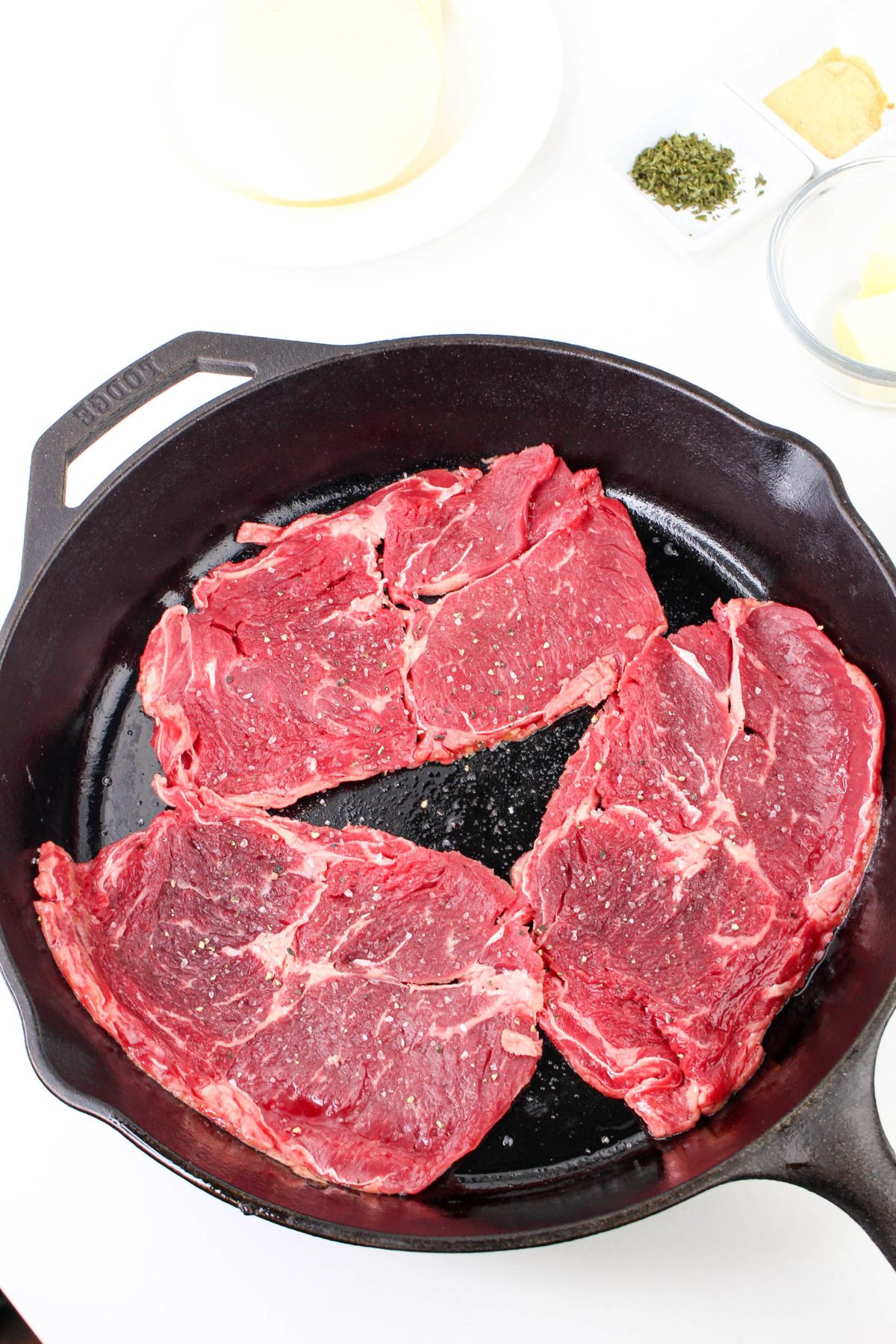 steaks being seared in a cast iron skillet.