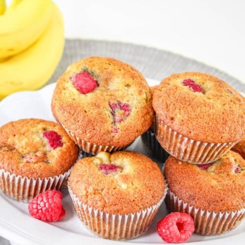 banana raspberry muffins stacked on a plate.