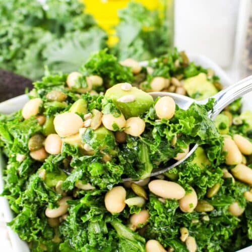 spoonful of kale and white bean salad held above a bowl.