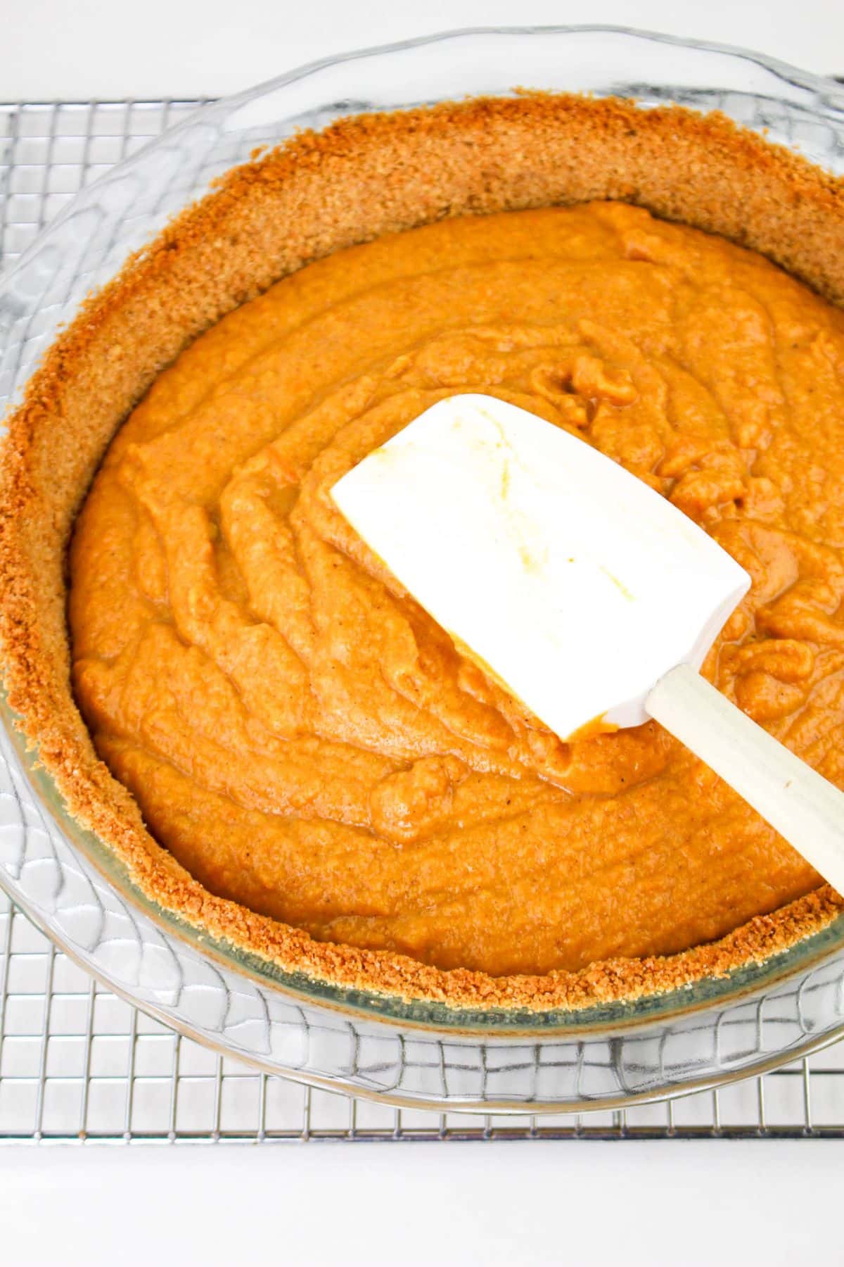 Sweet potato filling being spread into a graham cracker crust.