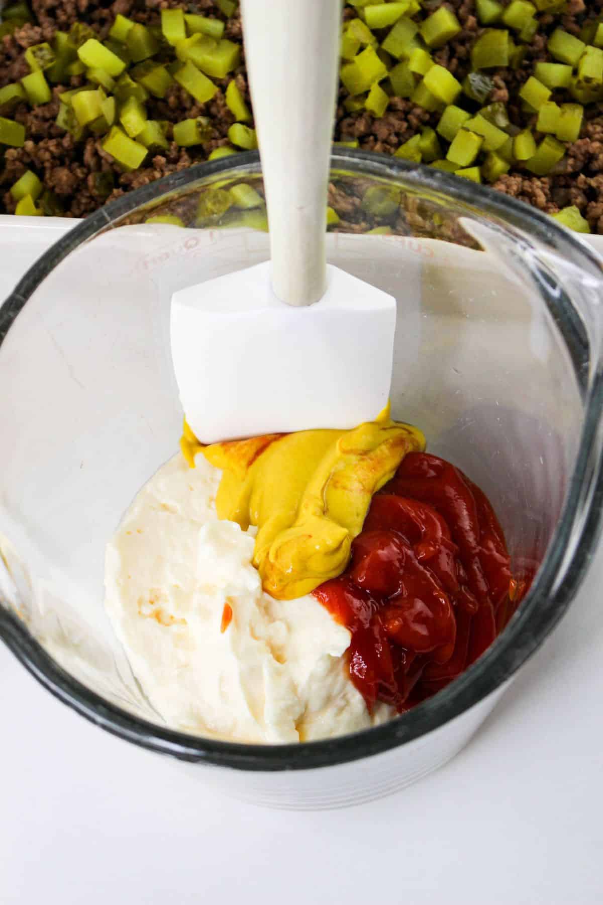 Ketchup, mustard, and mayo in a measuring cup.