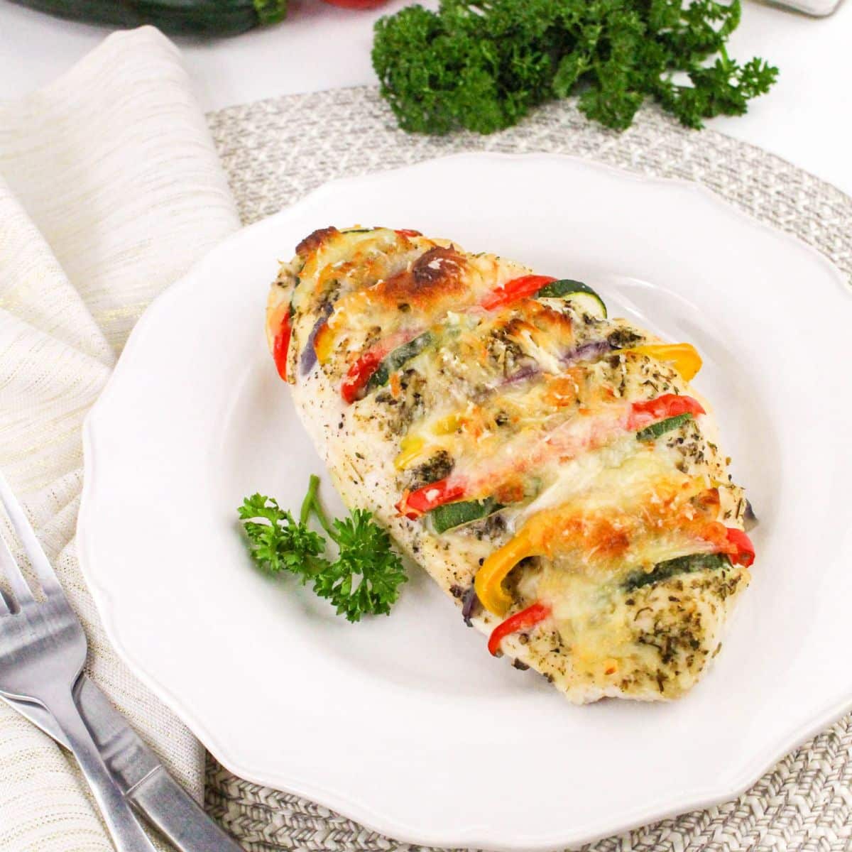 Plate of stuffed chicken breast with colorful bell peppers and herbs, garnished with parsley.