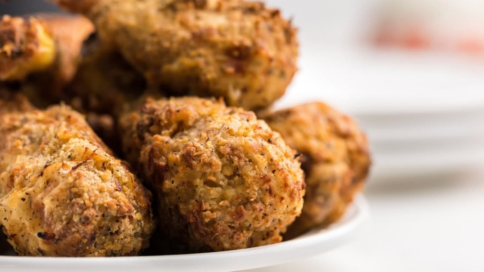 A close-up of a plate with crispy, breaded, fried chicken pieces stacked together.