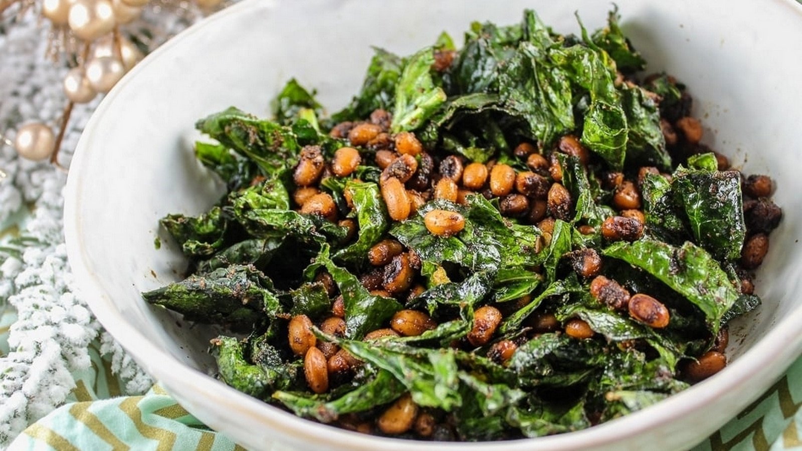 A bowl of sautéed kale mixed with roasted peanuts.