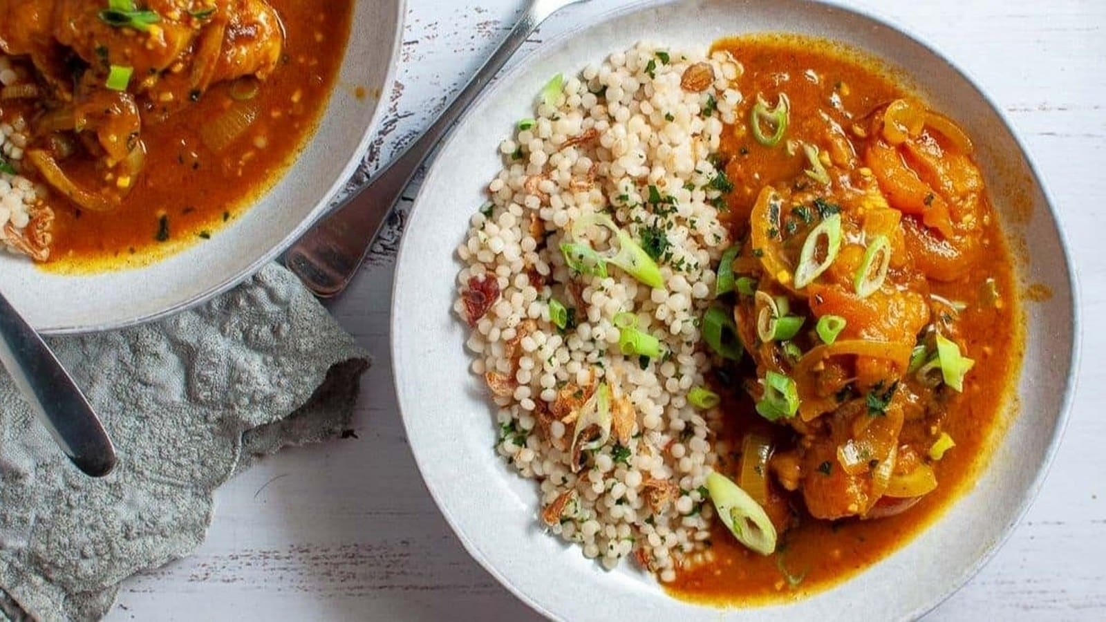 A plate of couscous and a vegetable stew garnished with sliced green onions.