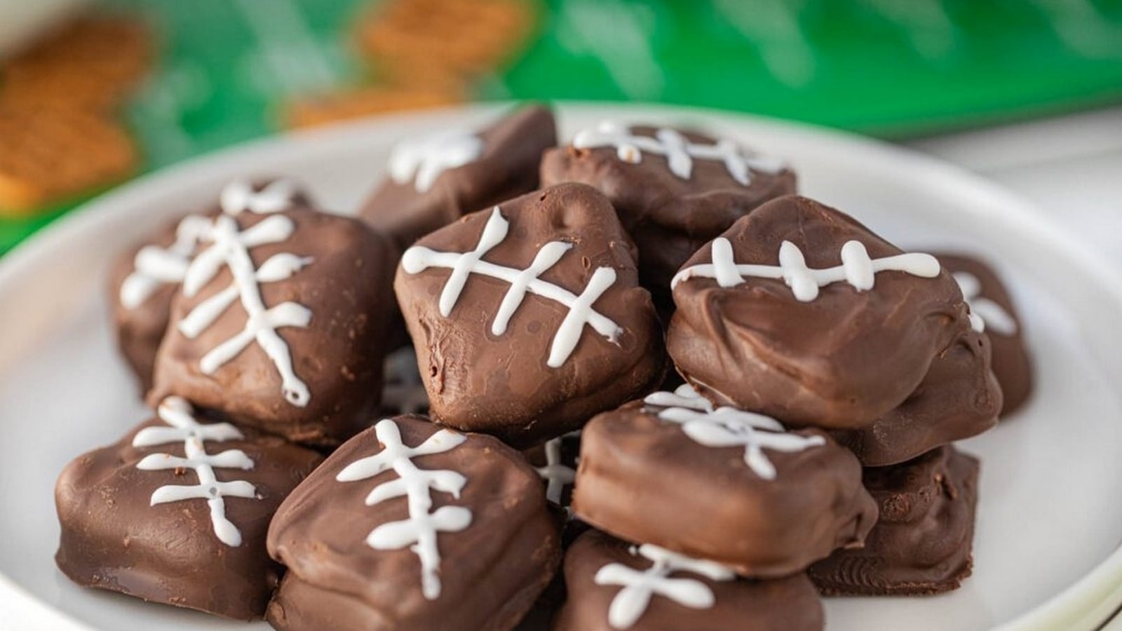 A plate of chocolate-covered treats decorated with white icing resembling football designs.