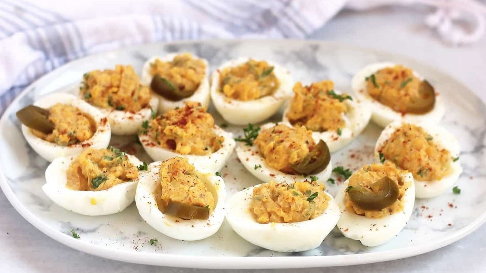 A plate of deviled eggs garnished with herbs and spices.