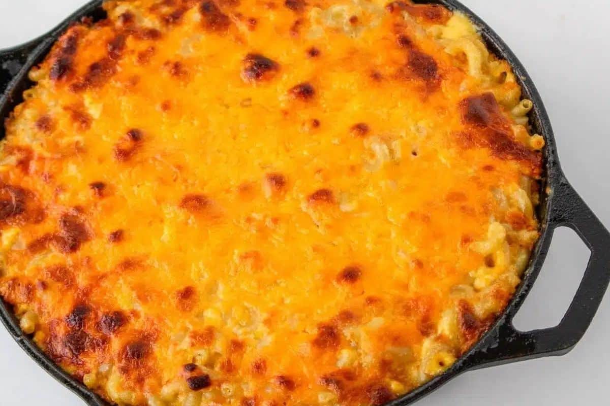 Baked macaroni and cheese in a black cast iron skillet, with a golden-brown, crispy cheese topping.