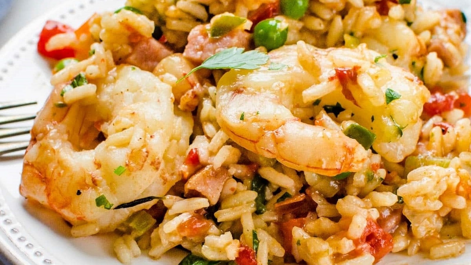 A plate of shrimp jambalaya with rice, shrimp, vegetables, and herbs.