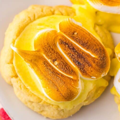 Close-up of a cookie topped with yellow cream and toasted meringue shaped like a fish.