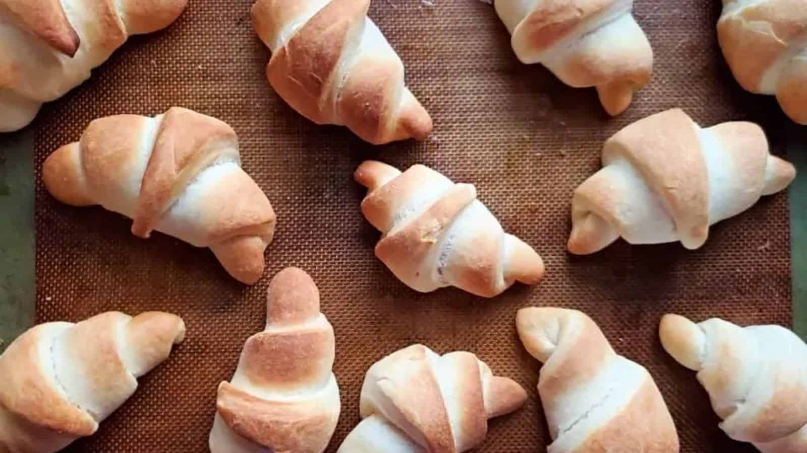 A baking tray with twelve golden-brown baked croissants arranged neatly.