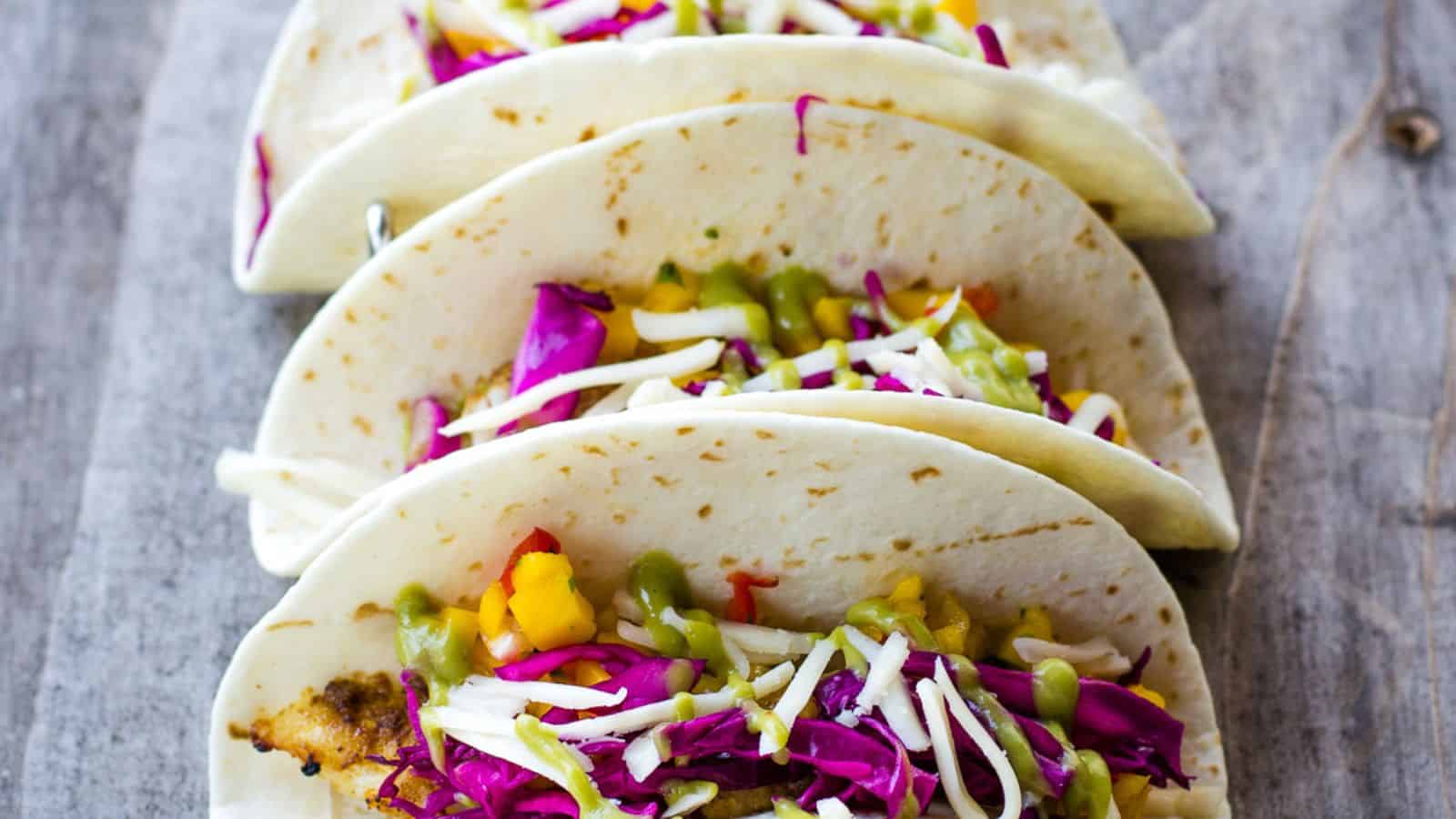 Grilled rockfish tacos assembled on a blue board.