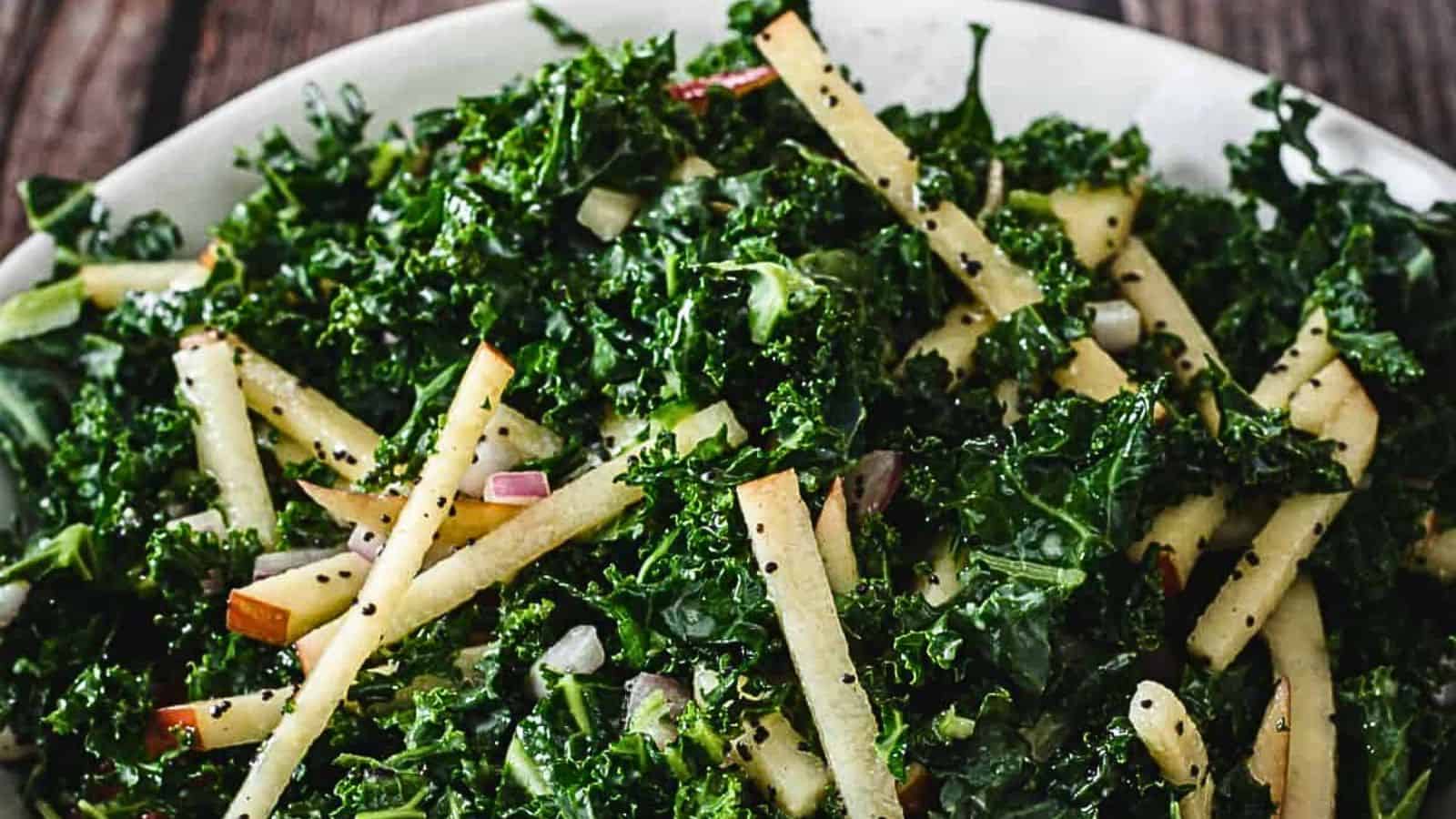 A salad with kale, apple slices, and poppy seeds.
