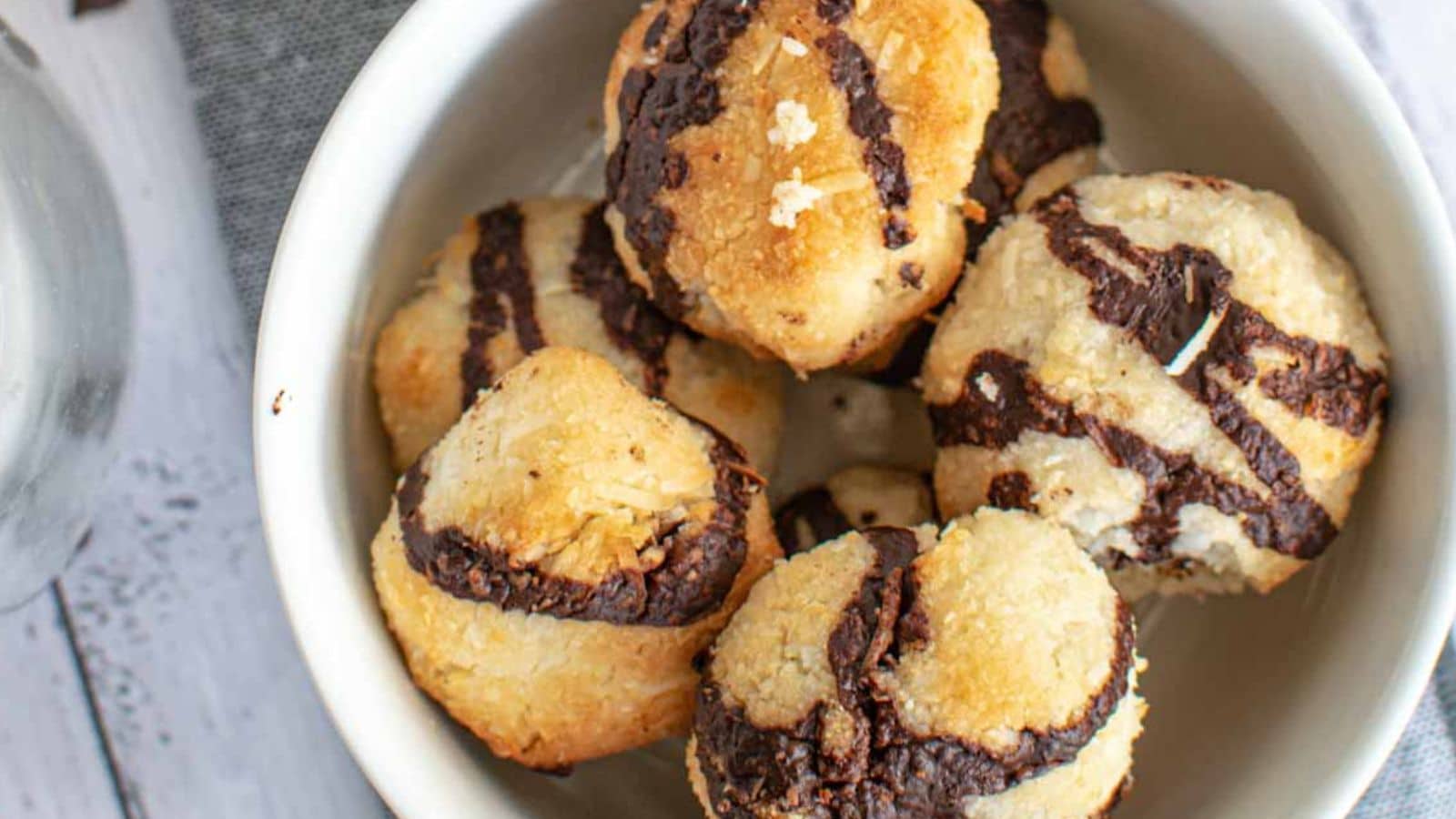 A bowl of five coconut macaroons drizzled with chocolate.