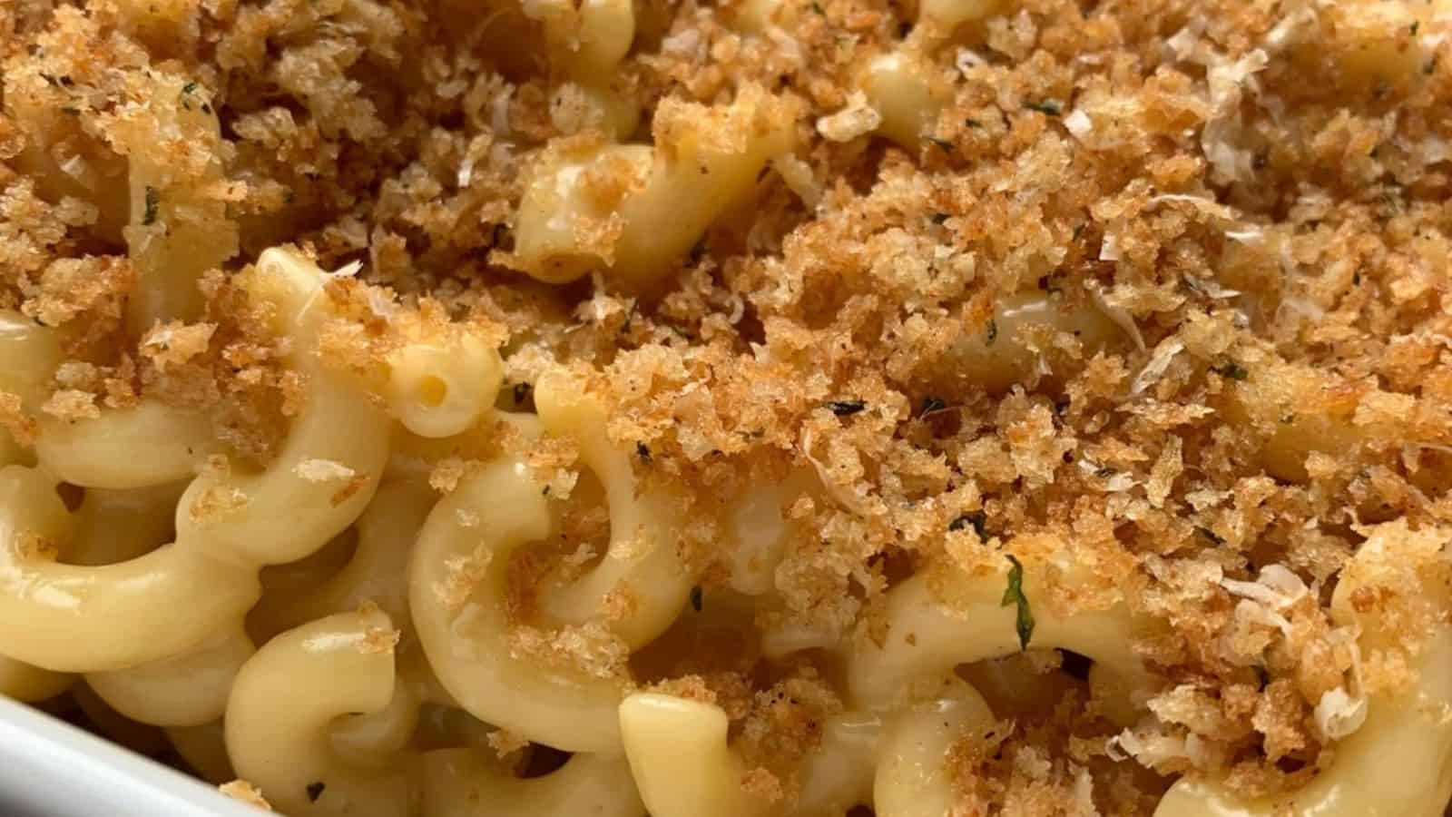 Close-up of macaroni and cheese with a crispy breadcrumb topping in a white dish.