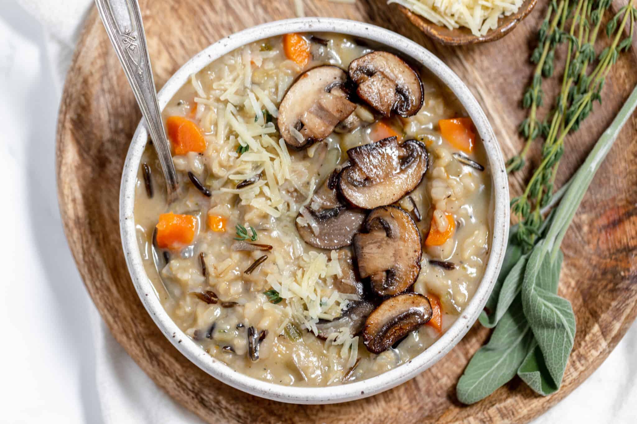 Wild rice and mushroom soup in a white bowl with sprigs of sage.