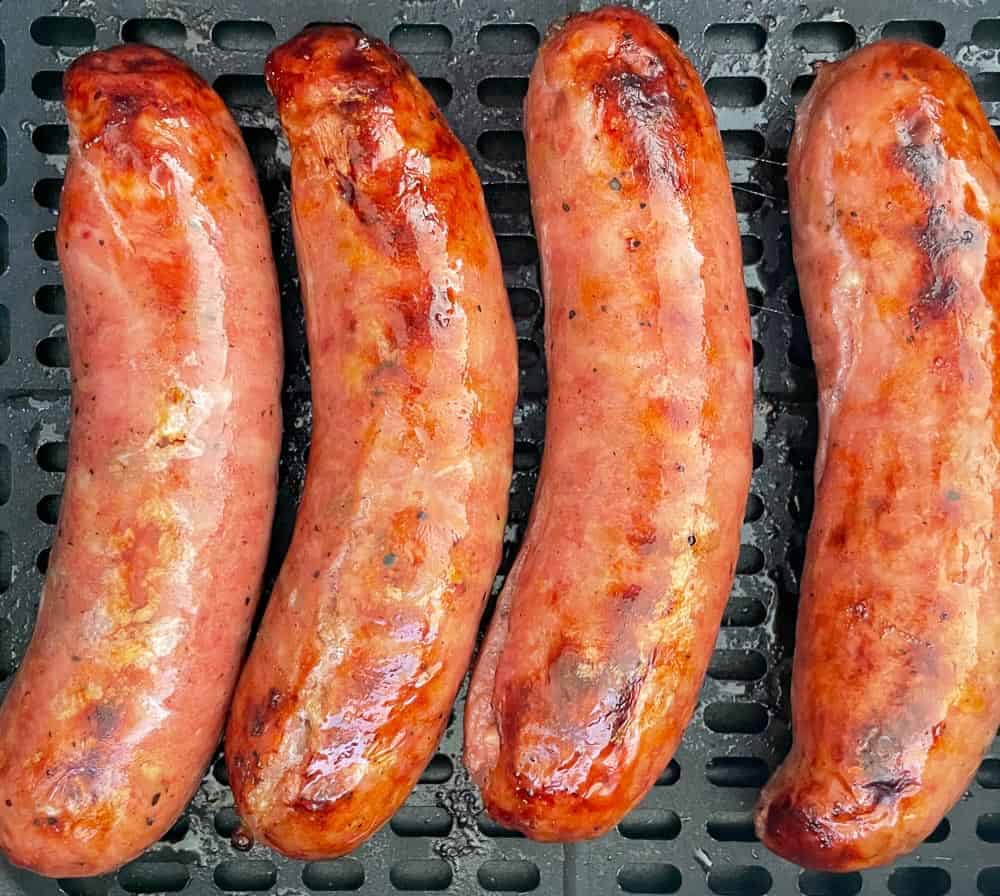 Grilled sausages in the basket of an air fryer.